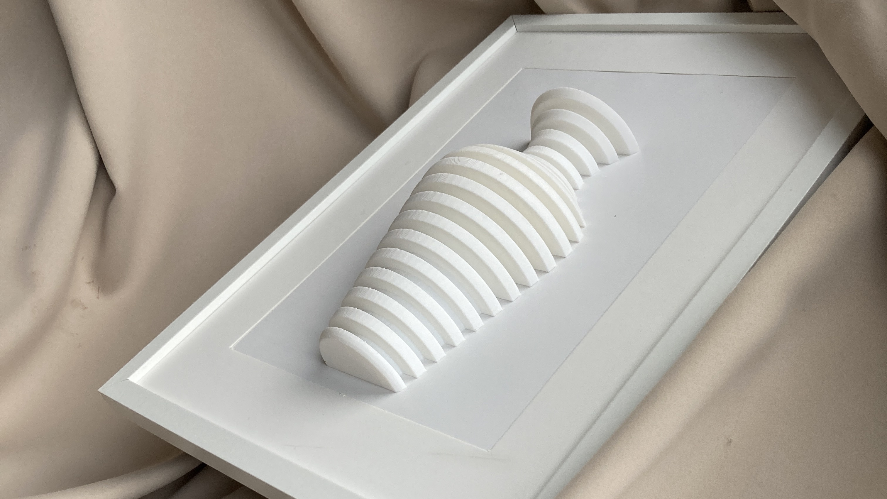 3D obraz so srdiečkovým reliéfom z vrstvených pruhov v bielej farbe — minimalistická dekorácia v bielom ráme